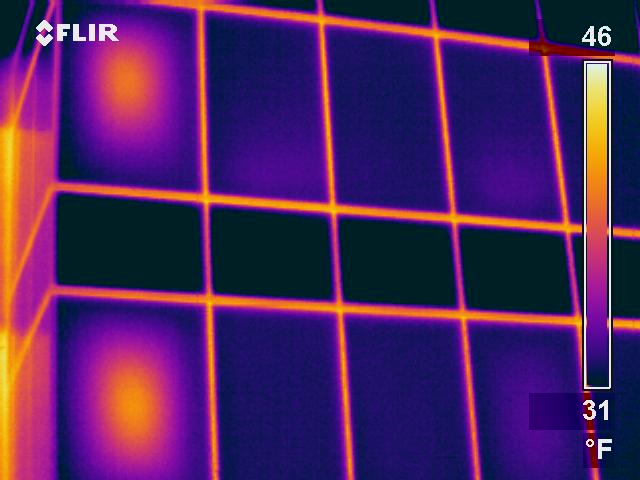 Thermogram shows warm thermal anomaly at the center of two IGU windows. Pattern typical of failed seals.